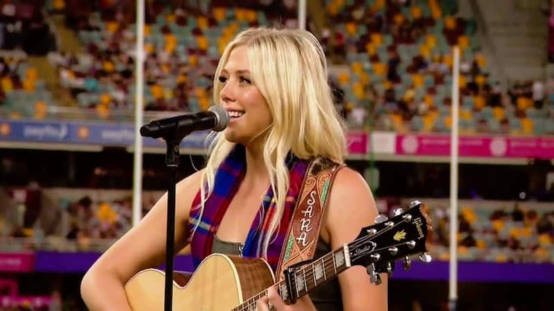 Sara Berki performs a cover of a John Denver song before an Australian football game, demonstrated that "Country Roads" lives on