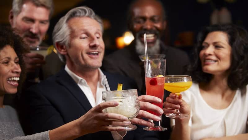 Friends with various alcoholic beverages, making a celebratory toast. By Monkey Business Images. Article on alcohol and health.