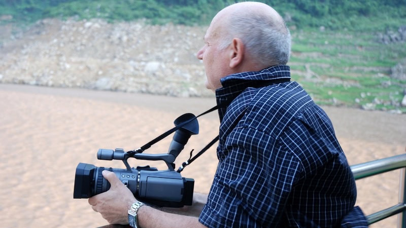 Man with movie camera, along the Yangtze River in China. By Gunold. Used with column on second-act artist.