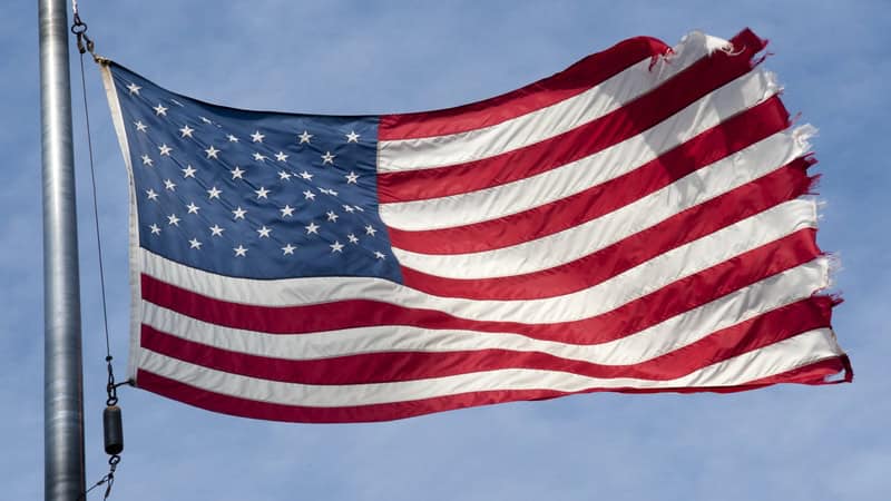 A tattered flag flying in the wind, ready for retiring an American flag. Image by Martin Haas.