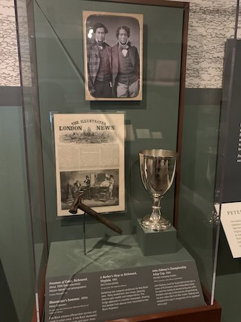Accomplishments of free Virginians shown in Un/Bound: portrait of two free men; a shoemaker's hammer, a barbershop in Richmond, and John Dabney's Championship Julep Cup