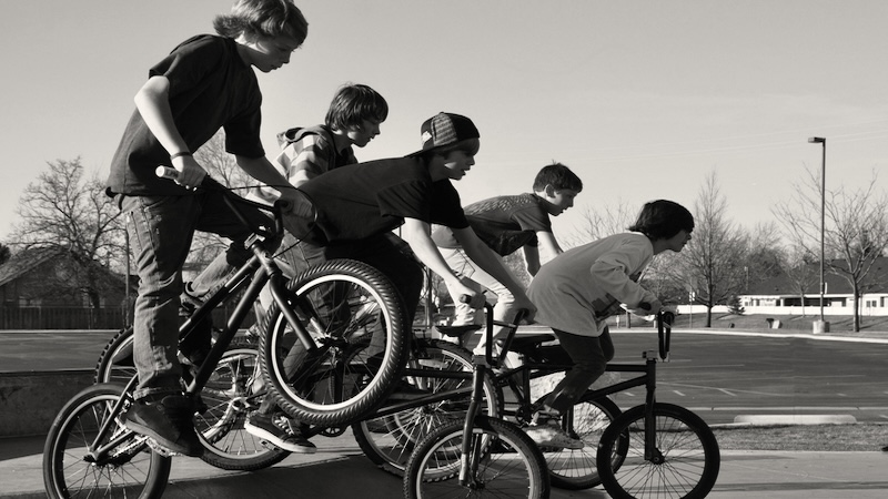 Young teenage boys on bikes, as in the story "We Were Explorers." Image by Brett Jorgensen