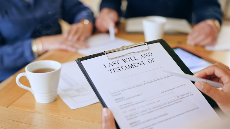 A last will and testament in the foreground, with a couple in the background. A couple disagrees over what to leave to adult children who are estranged. An inheritance talks, but what’s the right message to send? Advice columnist Eric Thomas weighs in.