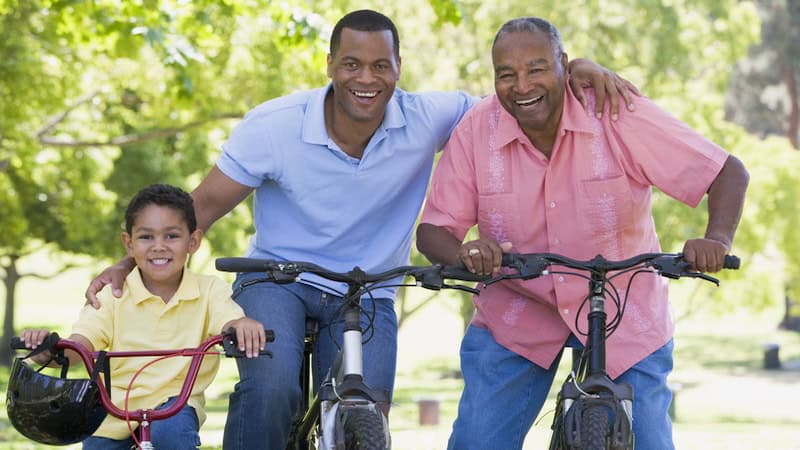 Grandson, son, and granddad on bikes. Son in the middle is now in the sandwich generation, part of the reason why Baby Boomers, Gen X have Different Approaches to Retirement