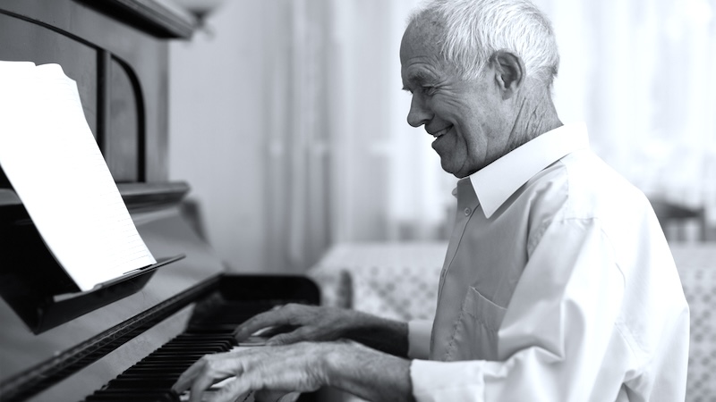 A man plays a home piano, with a smile on his face. "Enjoy Yourself," a classic old song! Image by Tatsiana Yatsevich
