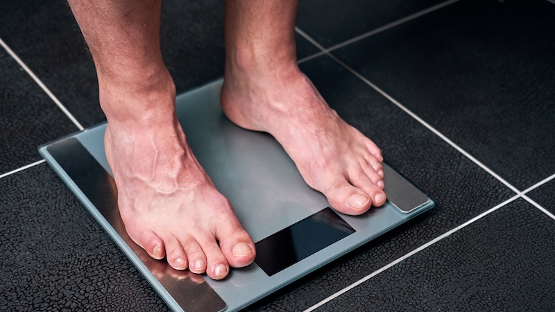 Man's feet on a bathroom scale. Does gaining a few extra pounds really matter?