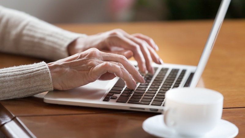 A woman's hands typing on a laptop. Used with the Boggle boat search puzzle