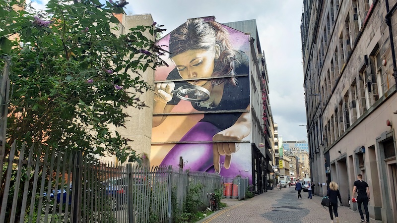 ‘Girl with a Magnifying Glass mural by Smug (Sam Bates) in Scotland's second city. Glasgow is both a workaday Scottish city and a cosmopolitan destination.