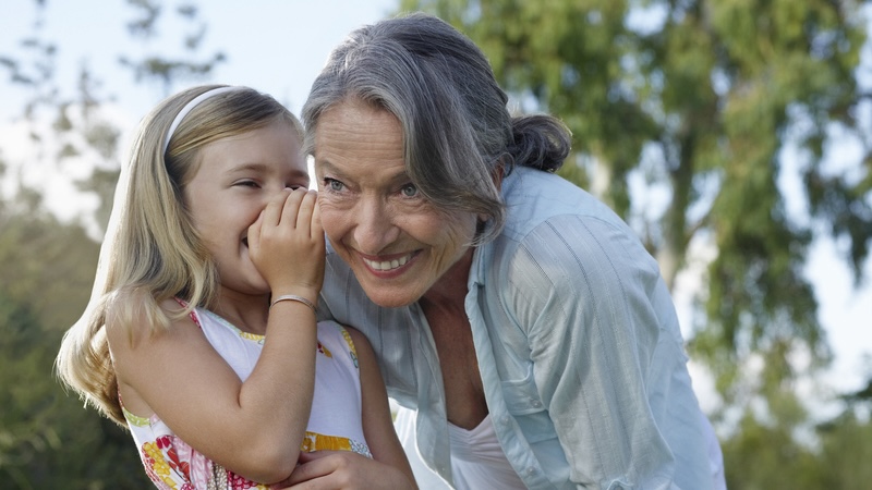 A granddaughter whispering into her grandmother's ear, both happy. By Photographerlondon. Used with article on turf wars over grandmothers' names