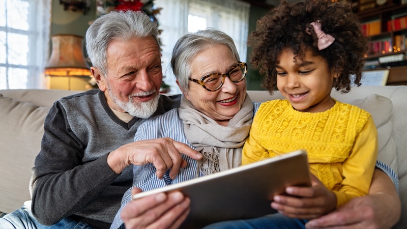 grandparents playing a computer puzzle with their granddaughter, like the Jumble puzzles with translations and coins. Image by Nd3000