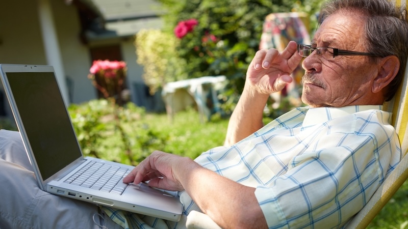 Man working on his laptop outside, maybe playing a puzzle. By Nyul.