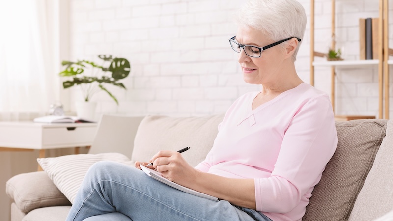 Senior woman writing, as her writing group helped her achieve her late bloomer boomer goals