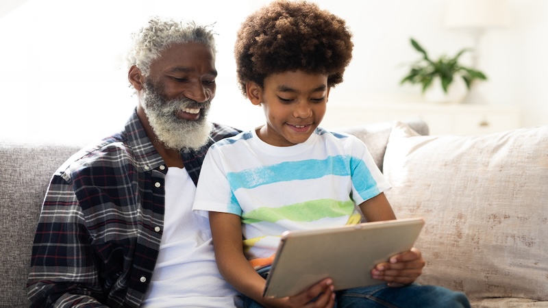 A granddad and grandson on a tablet, perhaps even playing the Jumble puzzles together. Image by Wavebreakmedia