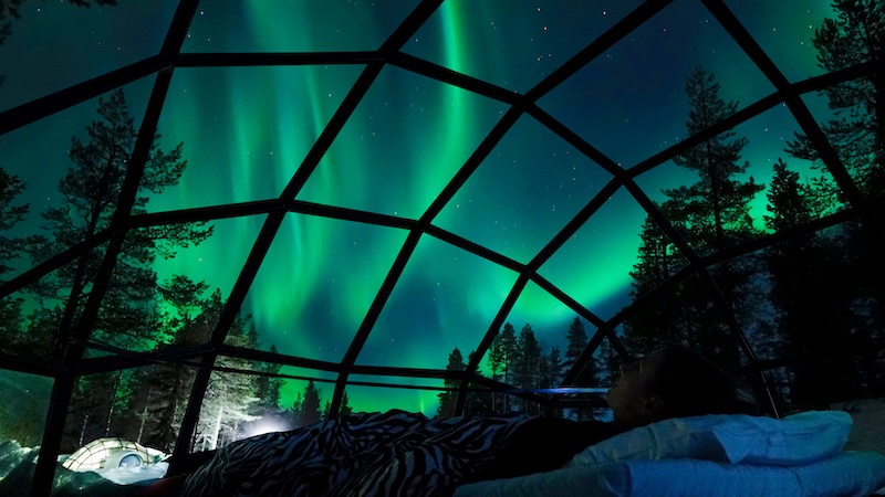 From the interior of a glass-enclosed cabin, with northern lights display outside. Noctourism refers to travel experiences that occur at night. (Dreamstime/TCA)