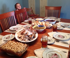 grand daughter peeping over the chair at Thanksgiving table, being grateful