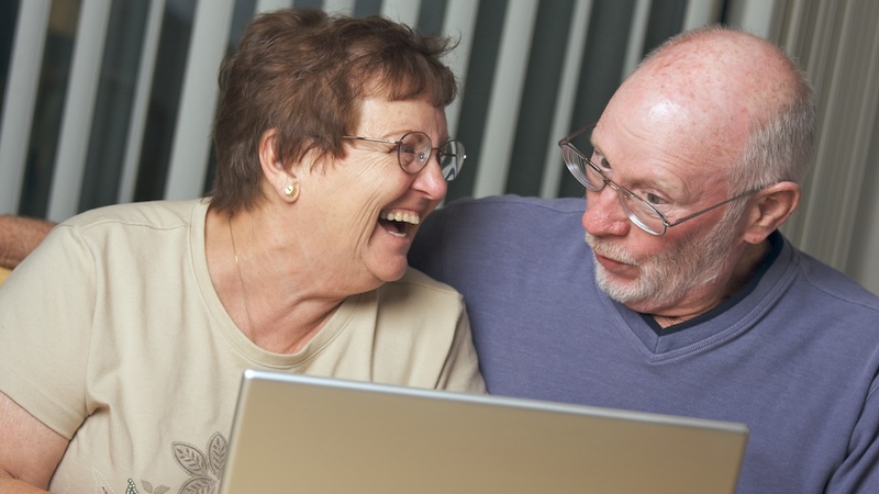 Senior couple on a laptop, perhaps playing a puzzle like Boggle the fruits. By Feverpitched.