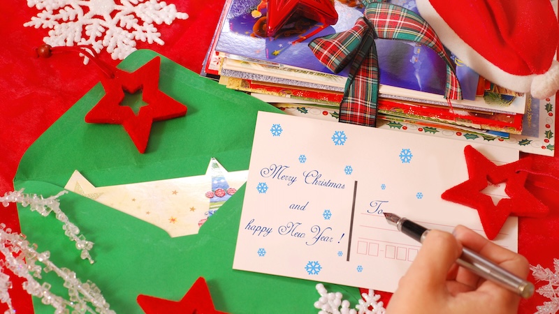 A person writing a Christmas card. Is it OK to share holiday greetings and divorce news at the same time?