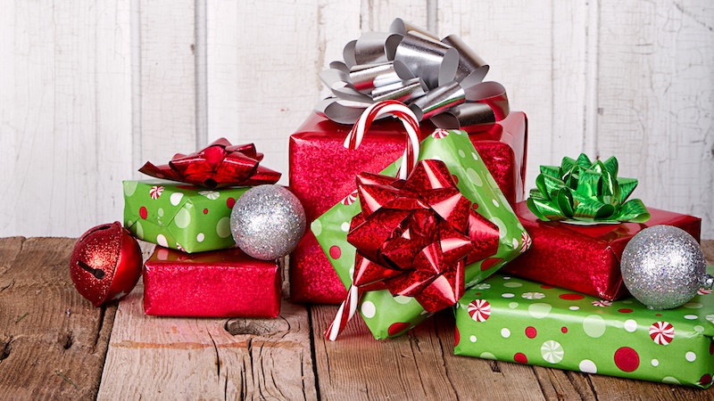 A pile of Christmas gifts on an old wooden table. By Sjhuls. Used with advice article on when gift exchange loses its luster