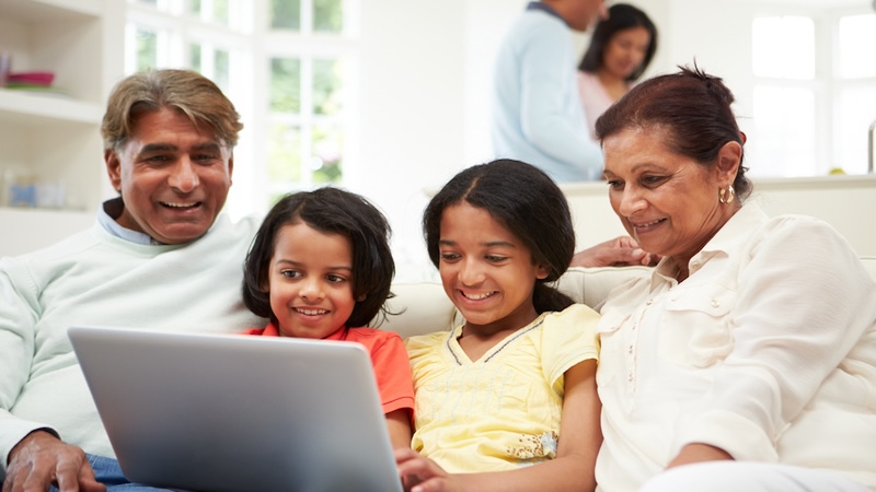 Grandparents and granddaughters on a laptop, perhaps playing the Jumble puzzles with a cat and a game