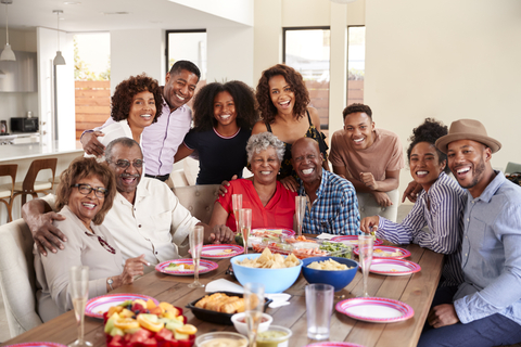 A large family gathered around a table at a family reunion. Monkey Business Images.