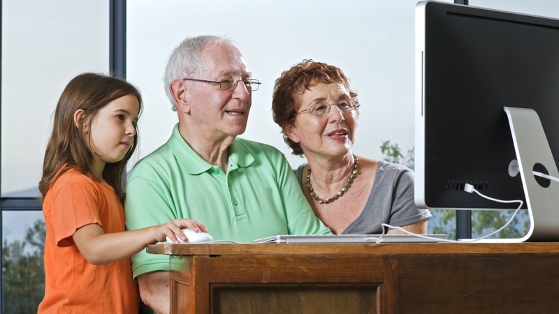 Grandparents and granddaughter on a computer, perhaps doing a puzzle like the Jumble with a cow and magician