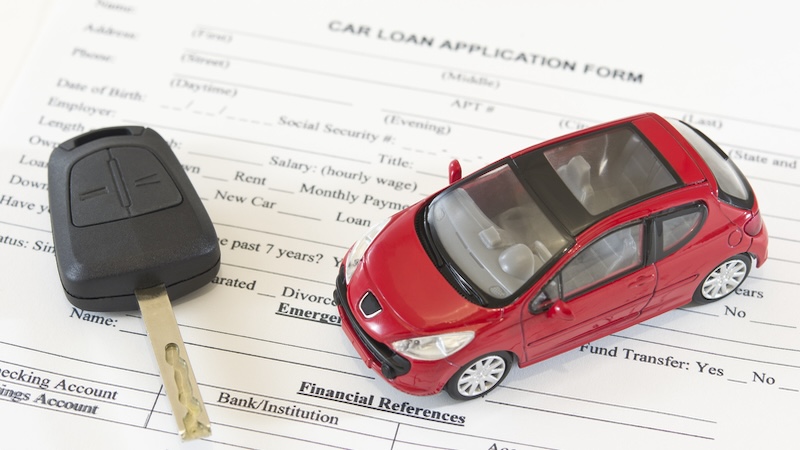 Car buying tips - key and small model car on a automobile loan application form