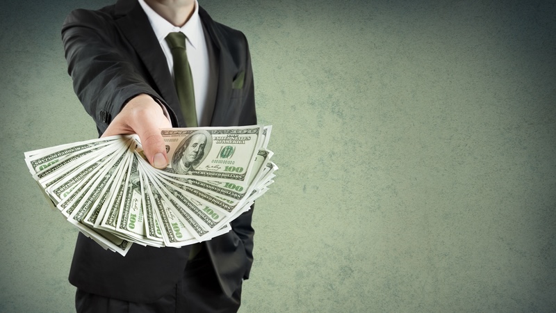 Man handing over a bunch of $100 bills, representing a large tax refund. Romolo Tavani