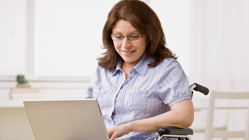 Woman in wheelchair working on laptop. Millions more Americans with disabilities have become eligible to contribute to an ABLE account. (Dreamstime/TCA)