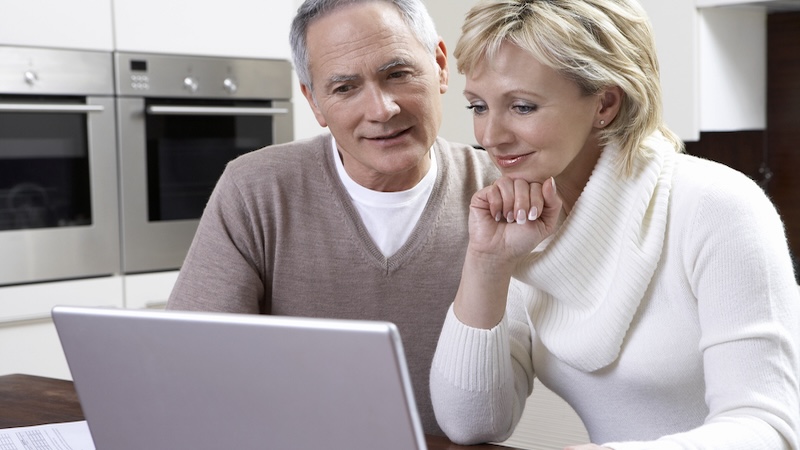 Couple on a laptop at home, possibly playing a puzzle like Boggle BrainBusters