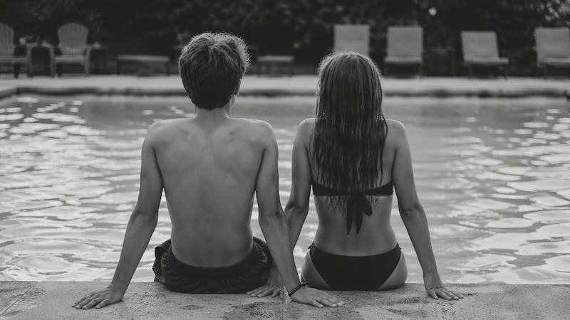 A teenage couple sitting on the edge of a pool, to accompany "How I Met My Wife Sandi" ChatGPT image