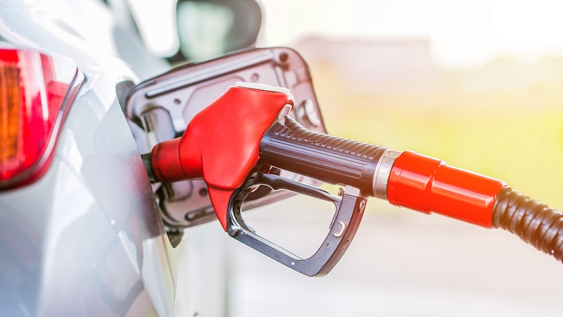 Fuel pump handle dispensing gas into a car, for article on how to save on driving costs.