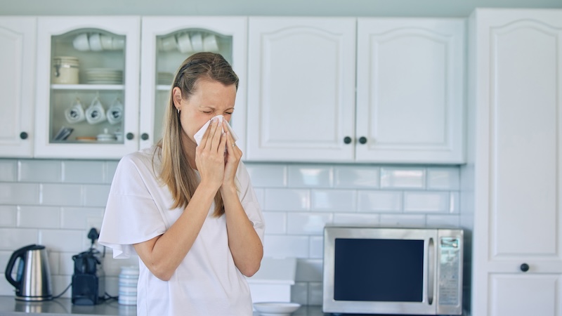 Foods can affect seasonal allergies, as this woman sneezing in her kitchen can attest.