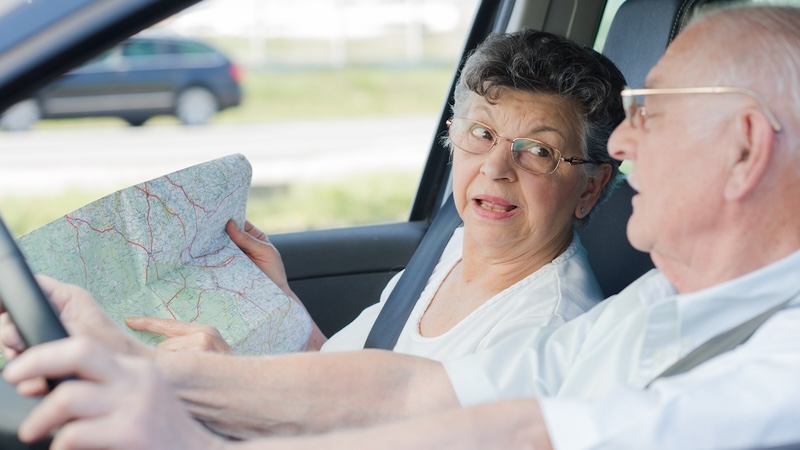 Should snowbirds drive 1,000 miles? An elderly man and woman in a car, looking at a map as he drives