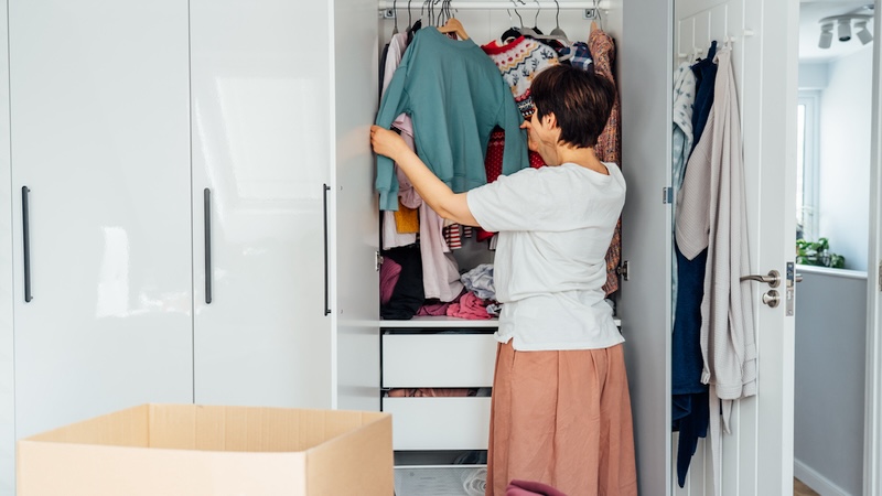 A woman going through her closet trying tips to declutter your home. Oksana Krasiuk