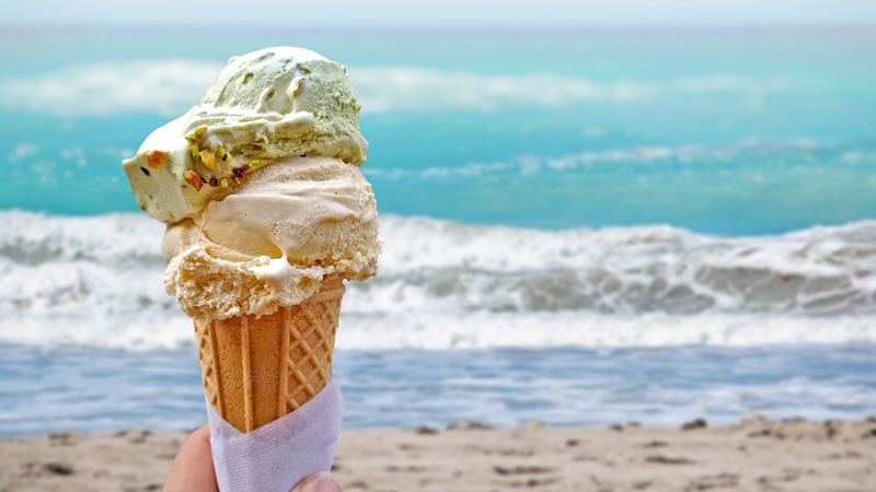 Ice cream cone held high at the beach, for an article on ice cream scoop shops