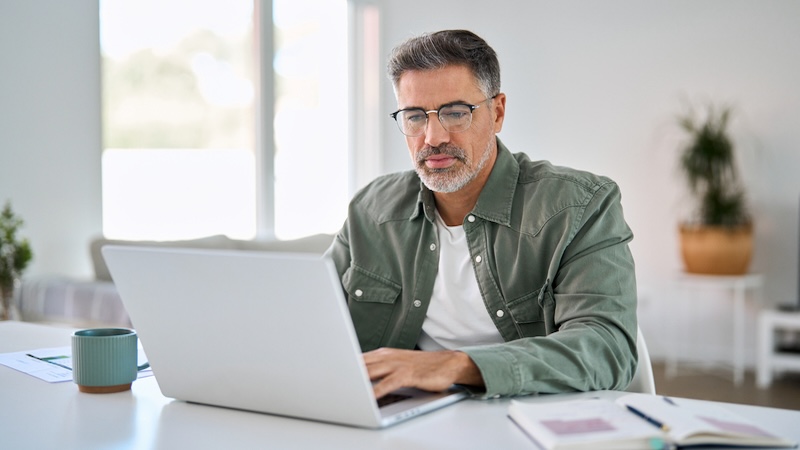 Man on a computer at home, wondering: Can AI Replace Financial Planners? Dark1elf