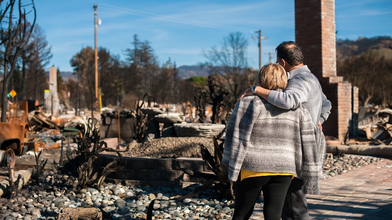 A couple looks at their home after it was destroyed by a forest wildfire. Vlad Teodor. Need to learn how to fireproof your home