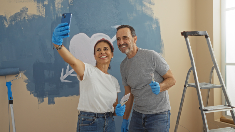 During a renovation boom, a couple is painting their home interior - posing with a heart painted on their wall to showcase their love. Aaron Amat