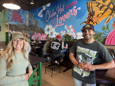 Maria Esquivel and Isaac Montoya in front of the mural at Cheba Hut "Toasted" Sub in Midlothian, Virginia. Credit: Steve Cook